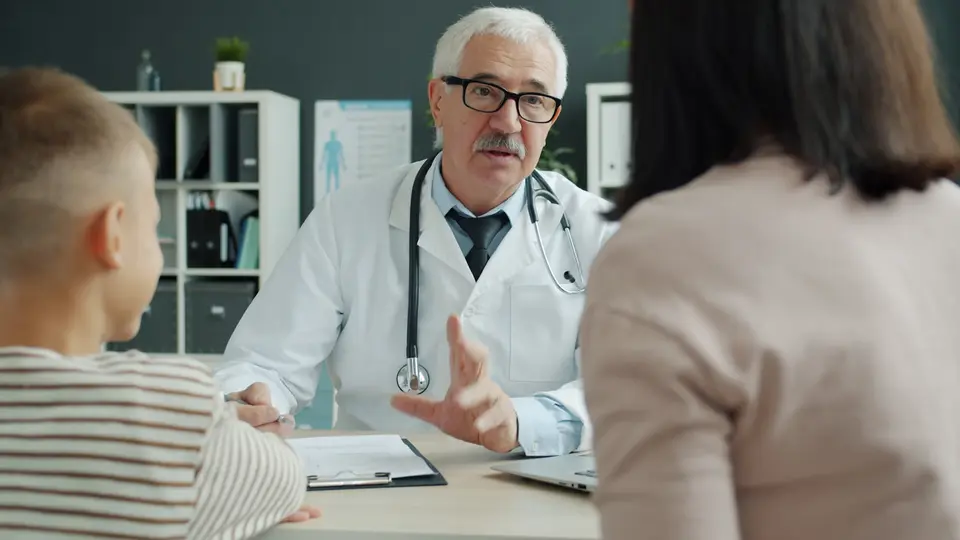 A doctor talking with a parent and child during a consultation