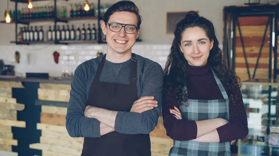 Two small-business owners standing together in their cafe